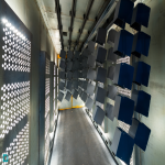 Powder Coating Chamber with Suspended Parts – Various metal objects, including perforated panels, undergoing the powder coating process in a specialized facility.
